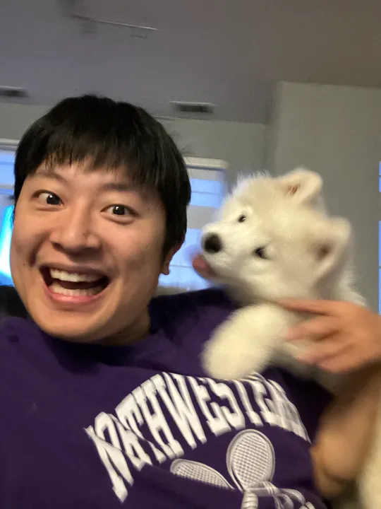 Jacky taking a playful, slightly blurry selfie while holding puppy Eleven