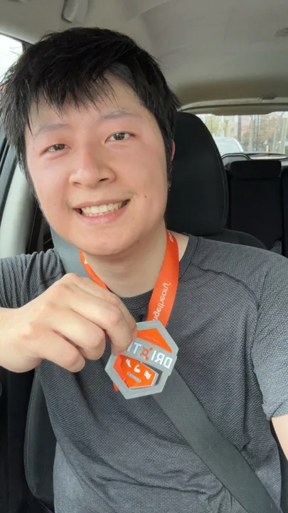 Jacky smiling and holding a medal earned through fitness training