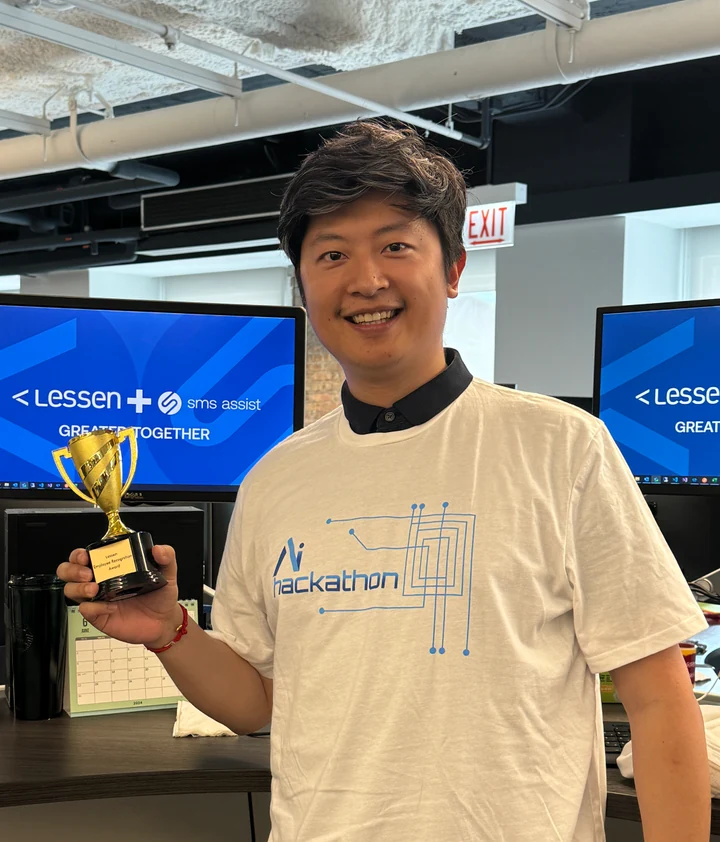 Jacky smiling in an AI hackathon T-shirt, holding an Employee Recognition Award.